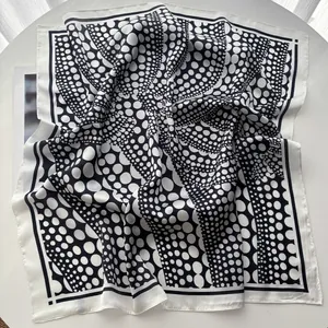 Detail of silk-satin scarf showing black and white polka dot patterns with premium pearlescent texture