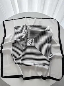 Macro detail of elegant black and white silk scarf with geometric border on a marble table
