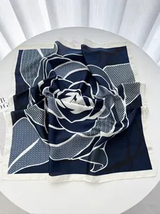 Detail of blue and white floral silk scarf featuring a large abstract rose and grid texture