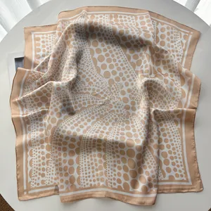 Detail of silk satin square scarf with beige and white polka dot patterns on a white table