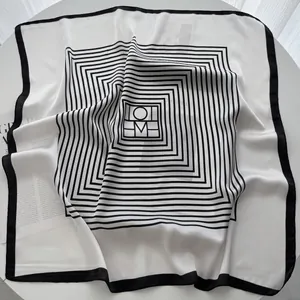 Detail shot of a black and white silk square scarf featuring a geometric M letter pattern