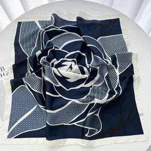 Detail of navy and white floral silk scarf with large rose patterns and satin finish