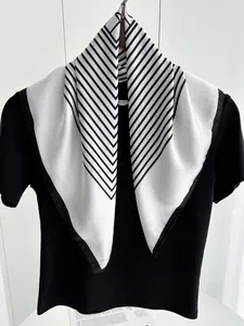Detail of minimalist black and white striped silk scarf tied on a black T-shirt