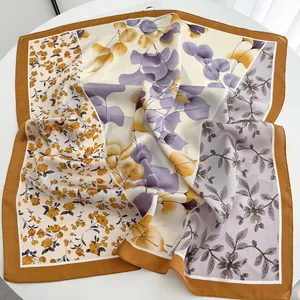 Vue détaillée d'un foulard en soie carré aux imprimés floraux élégants sur une table blanche
