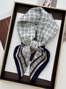 Close-up of geometric pattern silk scarf with dark blue border in a gift box