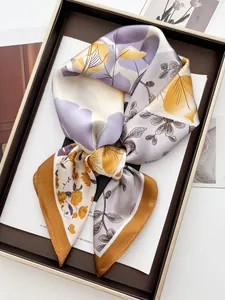 Détail d'un carré de soie aux motifs floraux abstraits violets et jaunes avec bords roulés