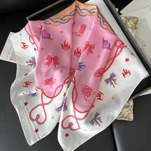 Detailed close-up of floral silk scarf with bow and heart illustrations in a black gift box