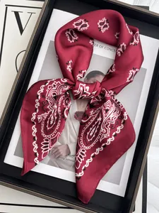 Close-up of deep red paisley silk scarf with satin texture tied in a bow on a magazine