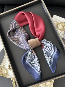 Detail of elegant silk scarf with red and gold paisley patterns on a black tray