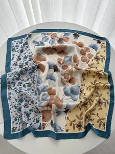 Gros plan sur le tissu d'un grand foulard carré aux motifs floraux et bords marine