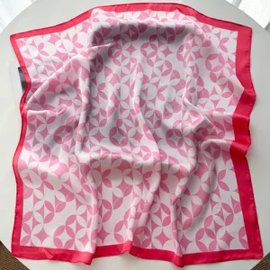 Detailed close-up of pink and white paisley silk scarf with elegant rolled hem on white table