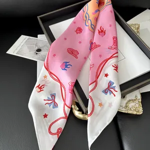 Detail of pink floral silk scarf with cowboy theme prints over black leather surface