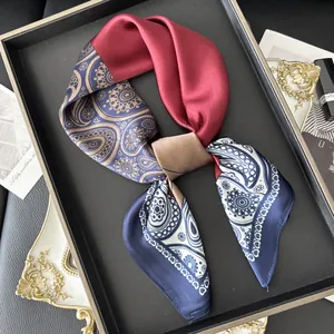 Detail of elegant paisley and crimson silk scarf displayed in a luxury accessory tray