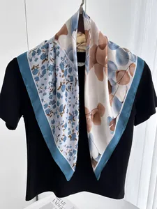 Détail d'un foulard en soie à fleurs et feuilles drapé sur un présentoir de cou noir