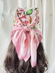 Detailed back view of an elegant pink floral satin scarf tied in a model's dark hair