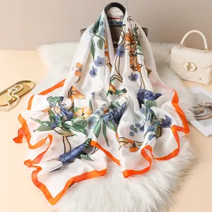 Floral silk scarf with vibrant orange edges on white faux fur background with accessories