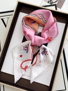 Detailed view of floral silk scarf with star patterns elegantly placed in a gold gift box