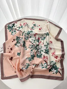 Détail du foulard en soie avec imprimé floral rose et crème et bordure marron