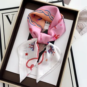 Detailed macro of floral twilly silk scarf tied in a premium brown gift box