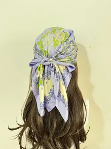 Detail of a lavender square silk scarf with floral patterns tied in a bandana style
