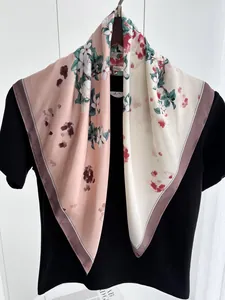 Détail d'un carré de soie aux motifs floraux roses et beige suspendu avec élégance