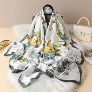 Detail of satin floral scarf with yellow flowers draped over a classic handbag