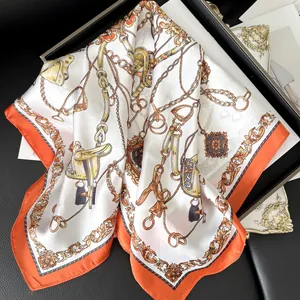 Close-up of a silk scarf with equestrian chain patterns and vibrant orange edges