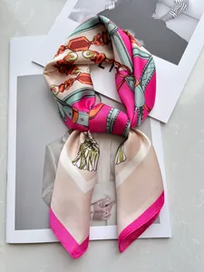 Flat lay of silk scarf with chain pattern on a fashion magazine and marble base