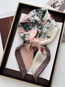 Détail d'un foulard en soie aux motifs floraux rose et vert dans un coffret cadeau
