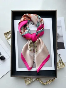 Detail of silk square scarf with orange floral and golden chain print on a magazine