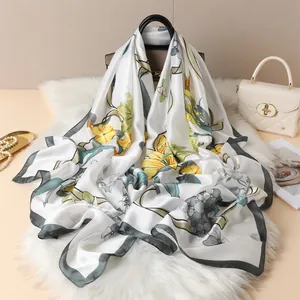 Elegant floral print satin scarf with yellow flowers draped over a luxury handbag