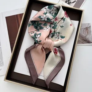 Détail d'un carré de soie avec imprimé floral et éclat satiné dans un coffret cadeau