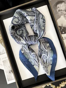 Dettaglio di un foulard di seta blu con motivo Paisley su un vassoio nero elegante