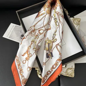 Detailed view of luxury silk scarf with equestrian chain print and orange border