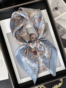 Gros plan du foulard en soie bleu clair avec motif paisley et finition satinée brillante