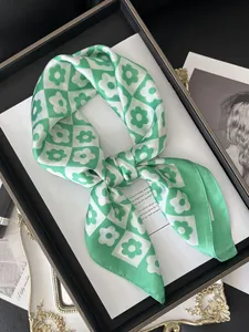Close-up of green checkered satin scarf with floral patterns on a display tray