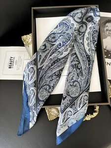 Dettaglio macro della sciarpa in seta paisley blu e bianca con orlo arrotolato su vassoio