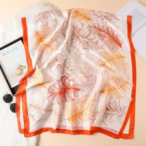 Detail of elegant feather print silk scarf with orange borders and SIYA Scarf branding