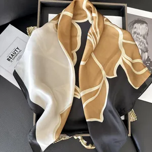 Elegante sciarpa in seta camelia oro e nera su vassoio con riviste di moda