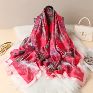 Detail of red and pink feather print silk scarf draped over a luxury white quilted handbag