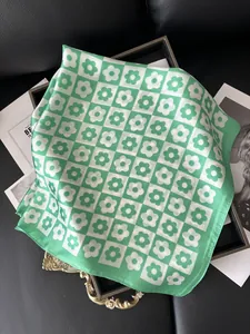 Green and white checkered floral silk scarf detail on a magazine flat lay setup