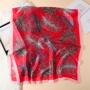 Detail of red silk scarf with elegant feather prints and smooth satin texture finish