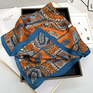 Détail d'un foulard en soie avec motif paisley et cœurs en tons orange et bleu