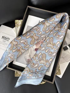 Détail du foulard en soie bleu clair à motifs paisley dorés sur un plateau vintage