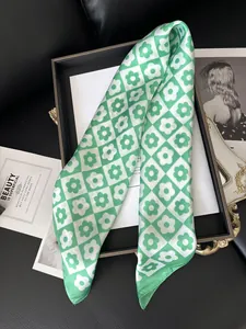 Detail of green checkerboard silk scarf with daisy pattern on a magazine display