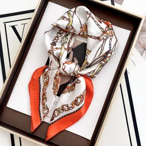 Detail of silk scarf with orange borders and classic chain patterns on white fabric