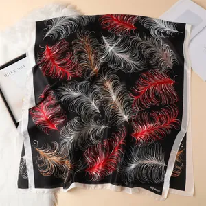 Detail of silk-like satin scarf featuring vibrant feather prints on a black background