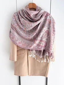 Détail d'une écharpe Paisley colorée avec des franges blanches sur un manteau élégant