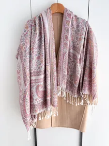Détail d'une écharpe à motifs paisley avec franges blanches sur un cintre en bois