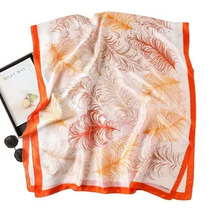Elegant silk-like scarf with orange feather print and chic travel accessories
